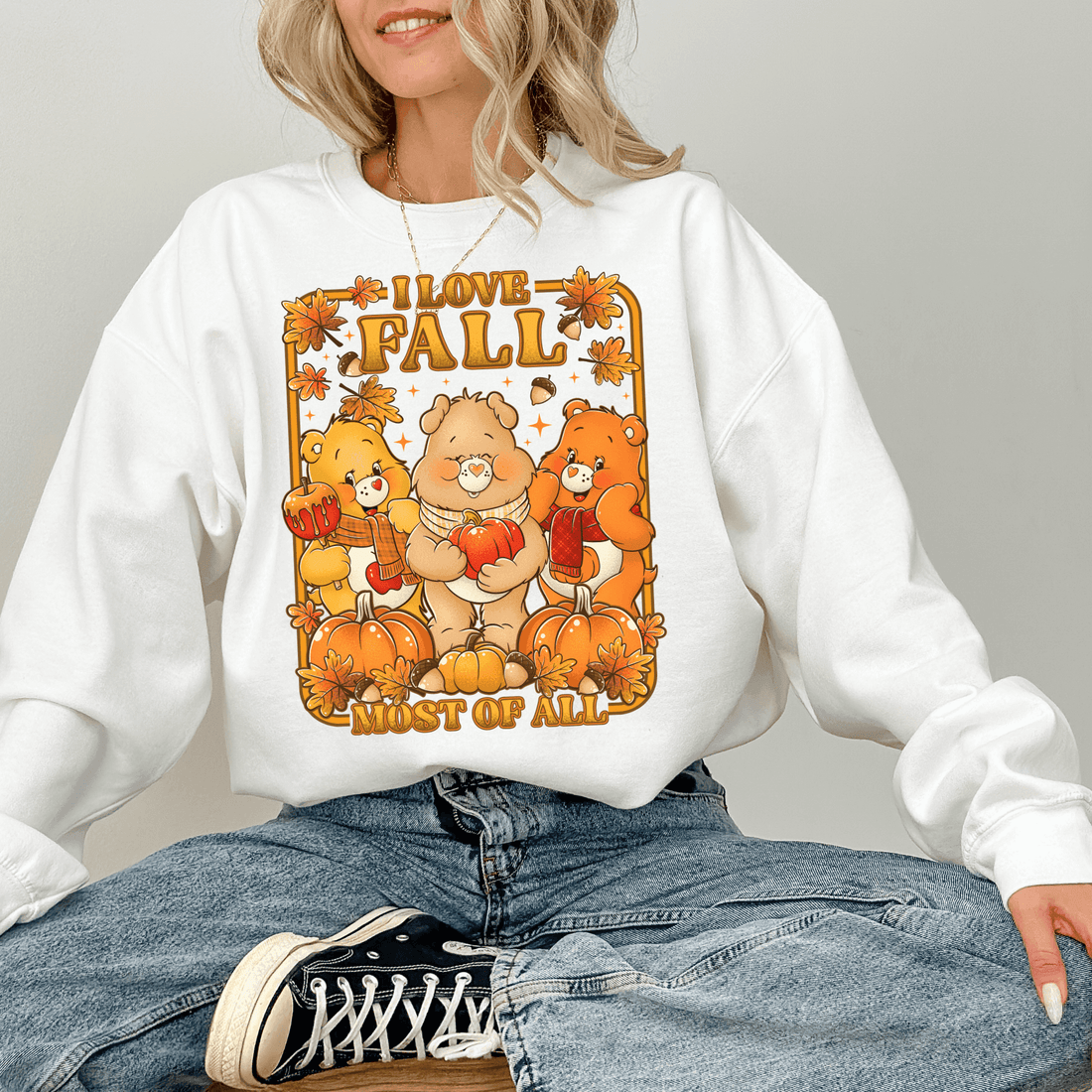 Person wearing a white sweatshirt with 'I love fall most of all' graphic design. cozy-fall-bear-sweatshirt