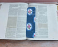 Open book with decorative floral page markers on a wooden surface.coquette-floral-bookmarks