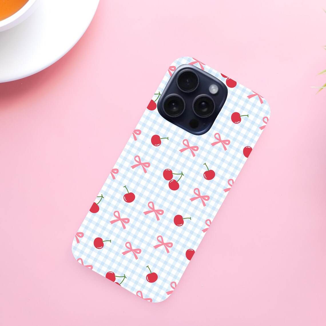 Phone case with cherry and bow pattern on a pink background.coquette-phone-case