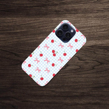 Phone case with cherry and bow pattern on a wooden surface.coquette-phone-case