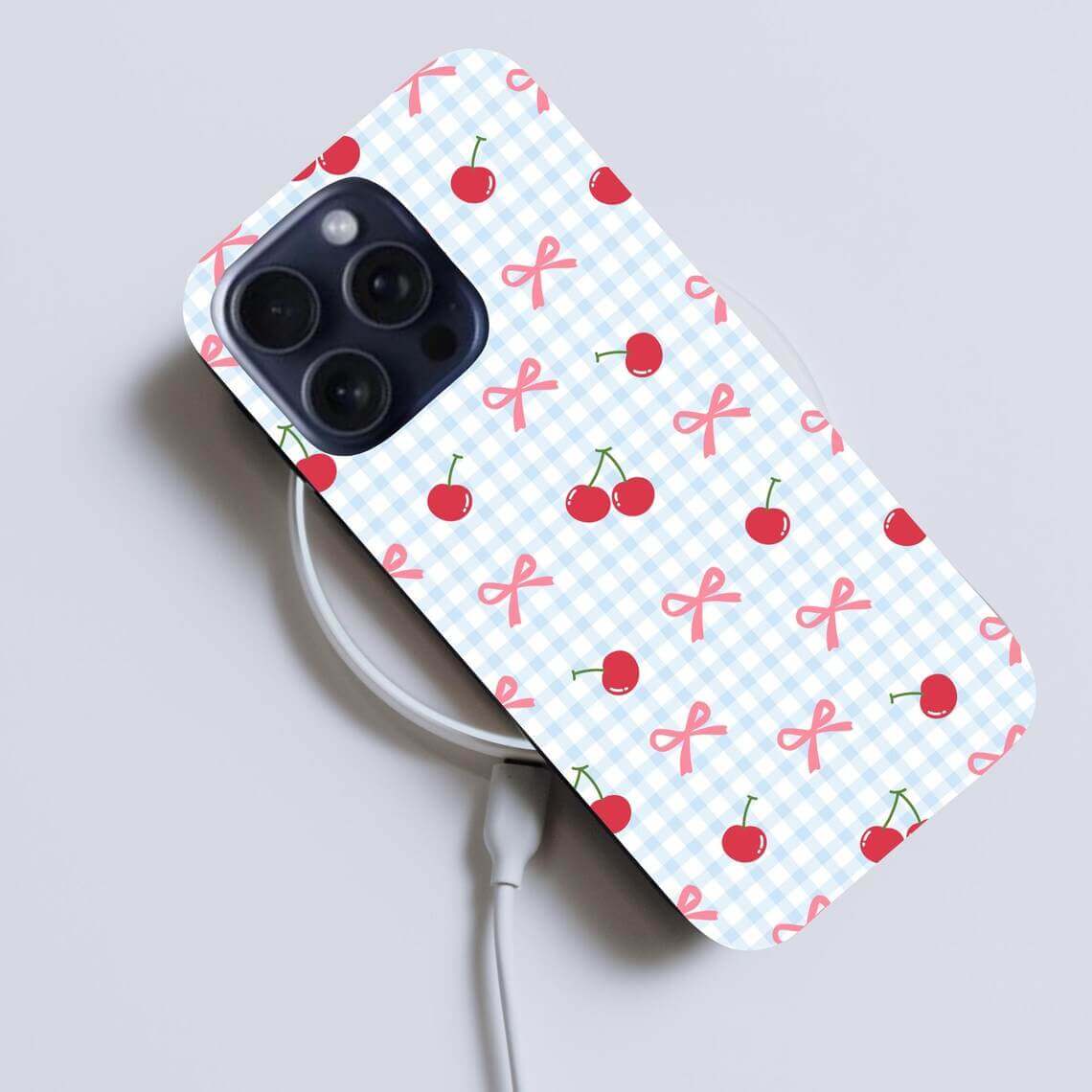 Phone case with cherry and bow pattern on a light gray background.coquette-phone-case