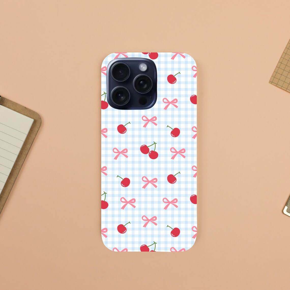 Phone case with cherry and bow pattern on a checkered background.coquette-phone-case