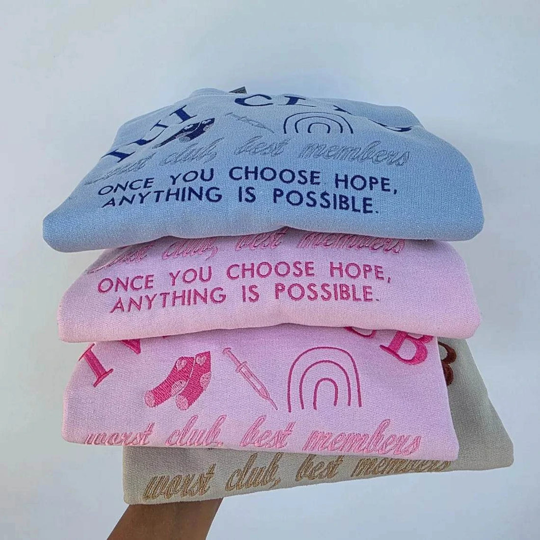 Pink and blue sweatshirts with 'IVE CLUB' and 'IUI CLUB' text on a white brick wall background. ivf-sweatshirt