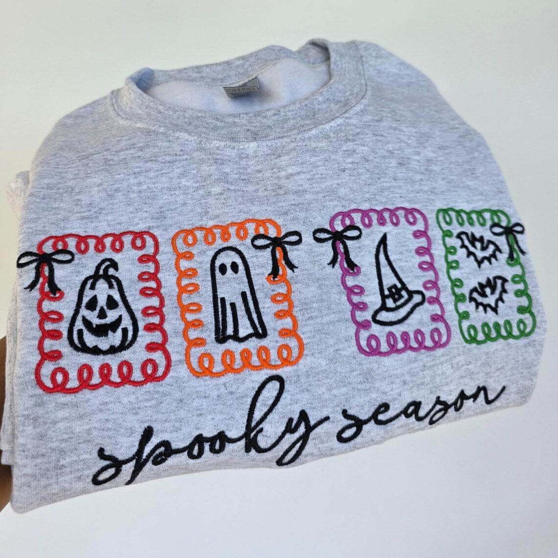 Gray shirt with Halloween-themed designs and text on a white background.halloween-embroidery-sweatshirt