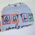 Gray shirt with Halloween-themed designs and text on a white background.halloween-embroidery-sweatshirt