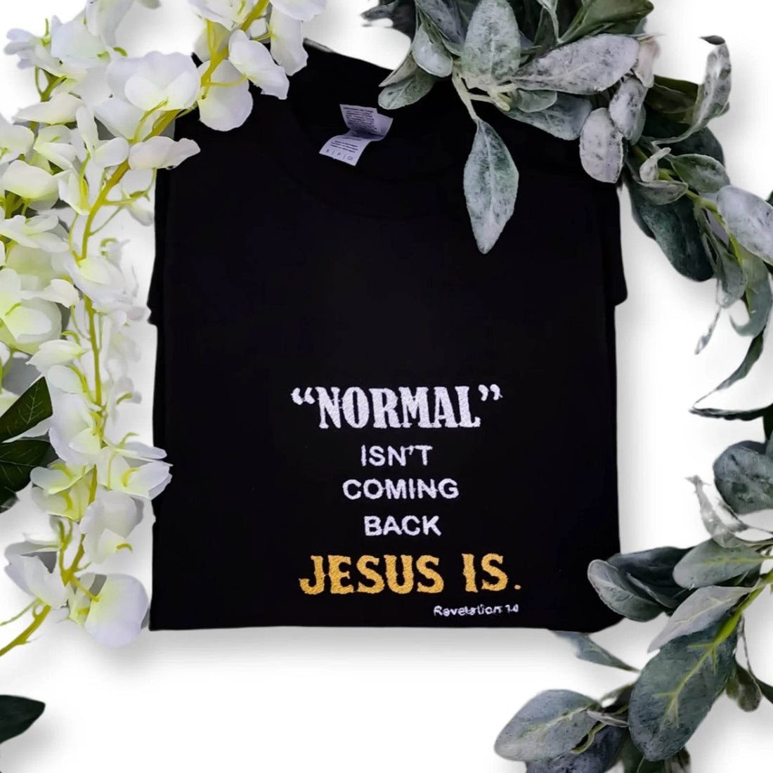 A black t-shirt with the text 'NORMAL ISN'T COMING BACK JESUS IS' embroidered in white and yellow across the front.jesus-revolution-tee