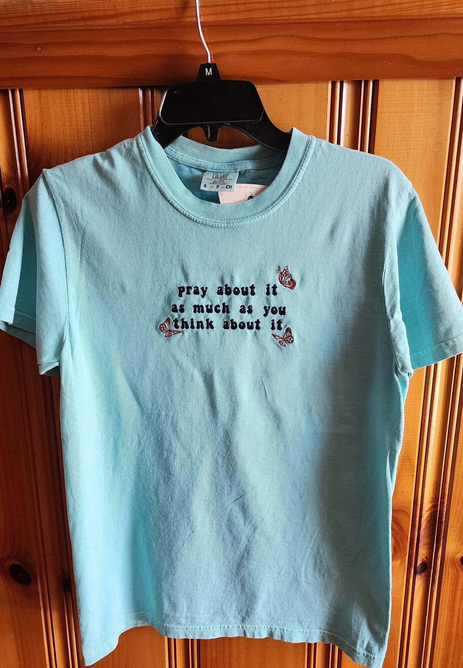 A blue t-shirt with the text 'pray about it as much as you think about it' printed on the front. pray-t-shirt