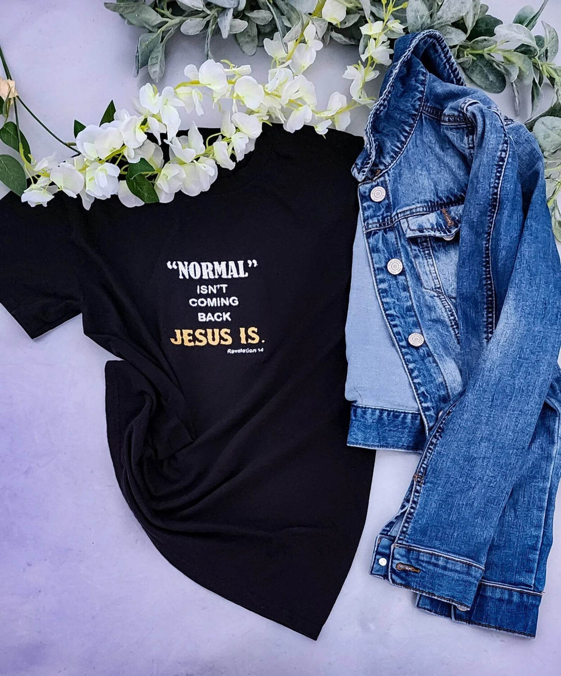 A black t-shirt with the text 'NORMAL ISN'T COMING BACK JESUS IS' embroidered in white and yellow across the front.jesus-revolution-tee