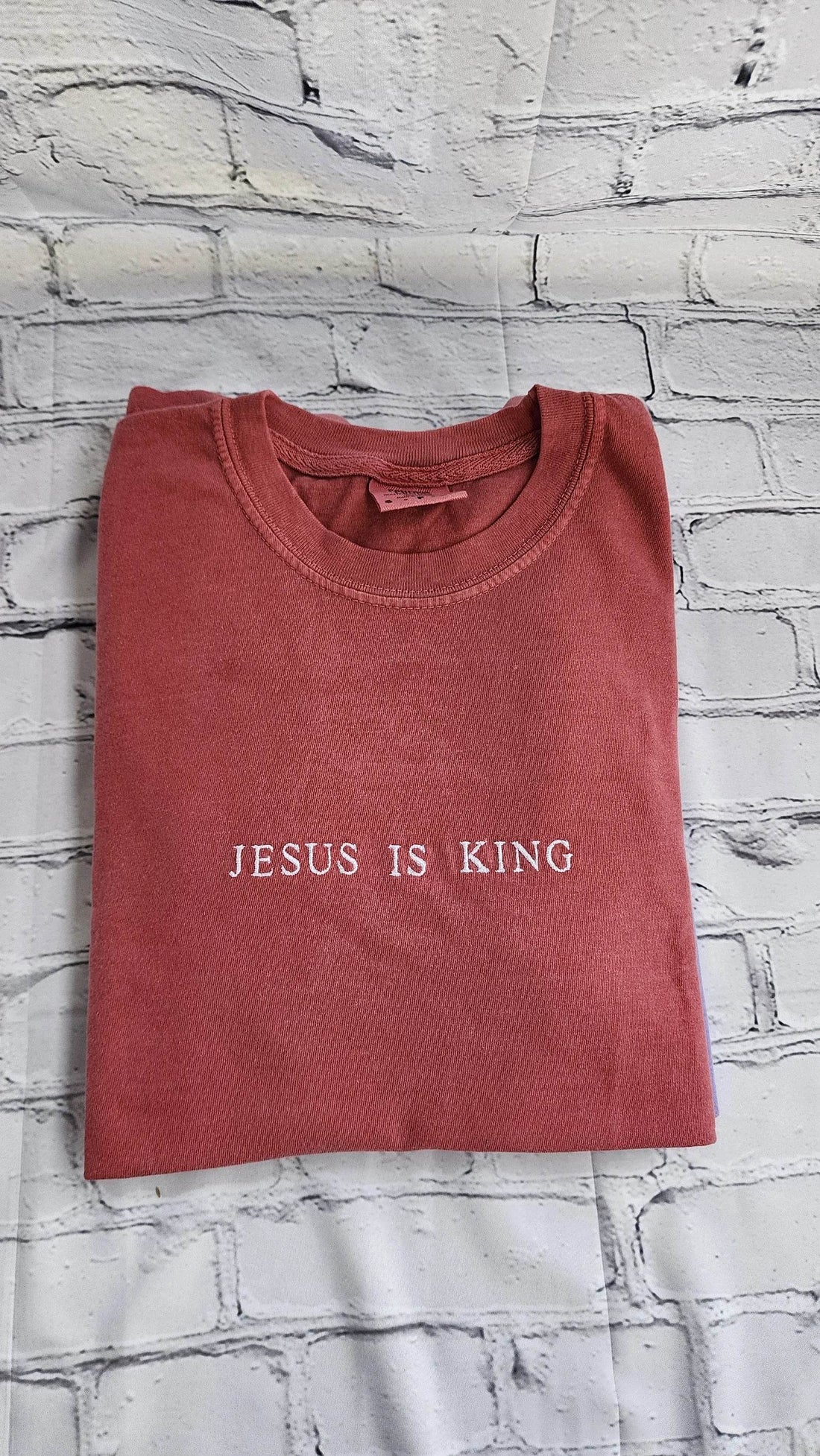 A pink short sleeve shirt with the phrase 'Jesus Is King' embroidered in a darker color across the front.jesus-is-king-shirt