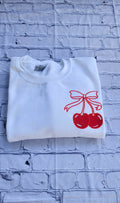 Folded White Sweatshirt Showing Cherry Bow Design