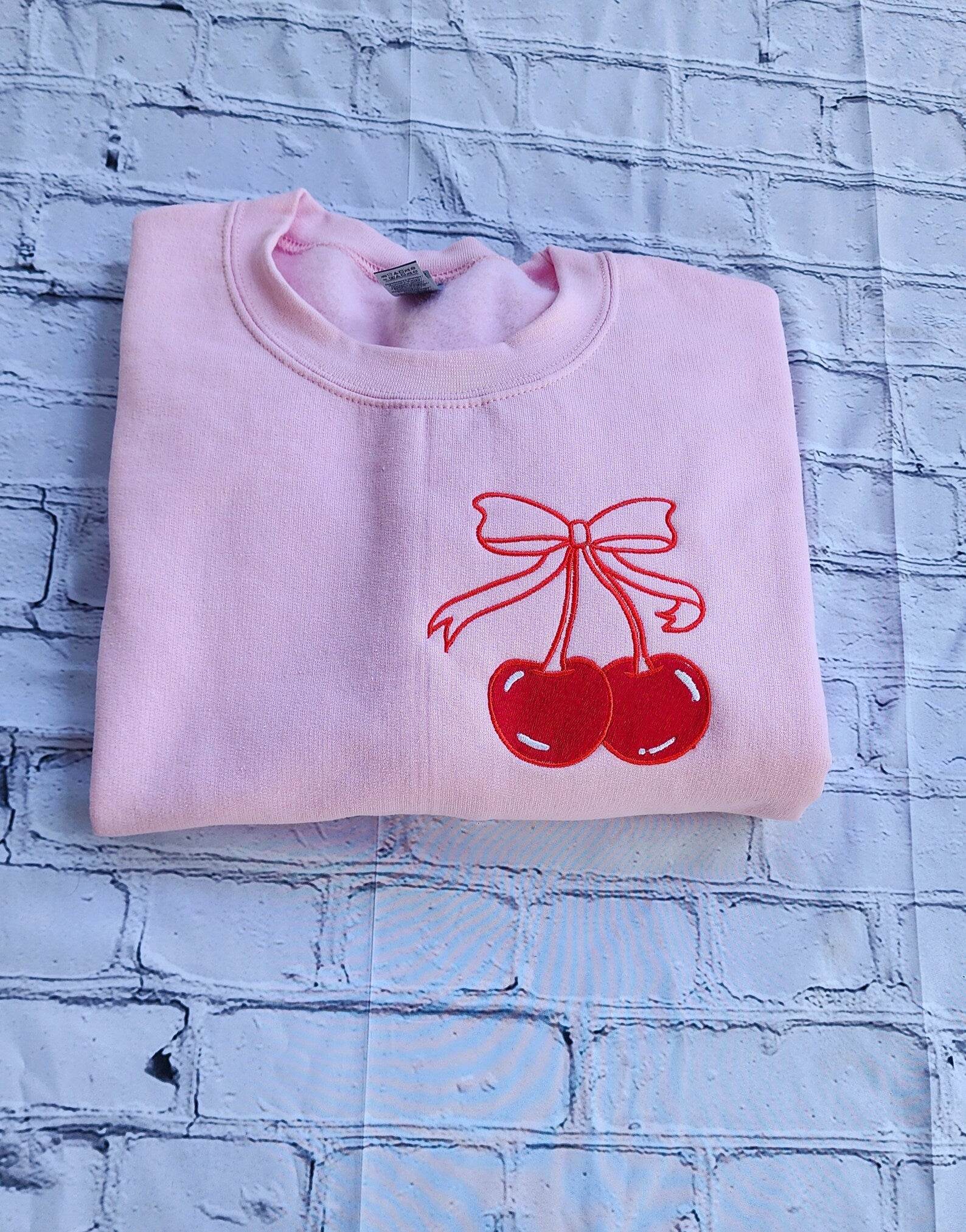 Folded pink Sweatshirt Showing Cherry Bow Design