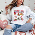 A woman sitting and smiling, wearing a white sweatshirt with a Valentine's Day-themed graphic, surrounded by red heart-shaped balloons.valentines-sweatshirt-for-women