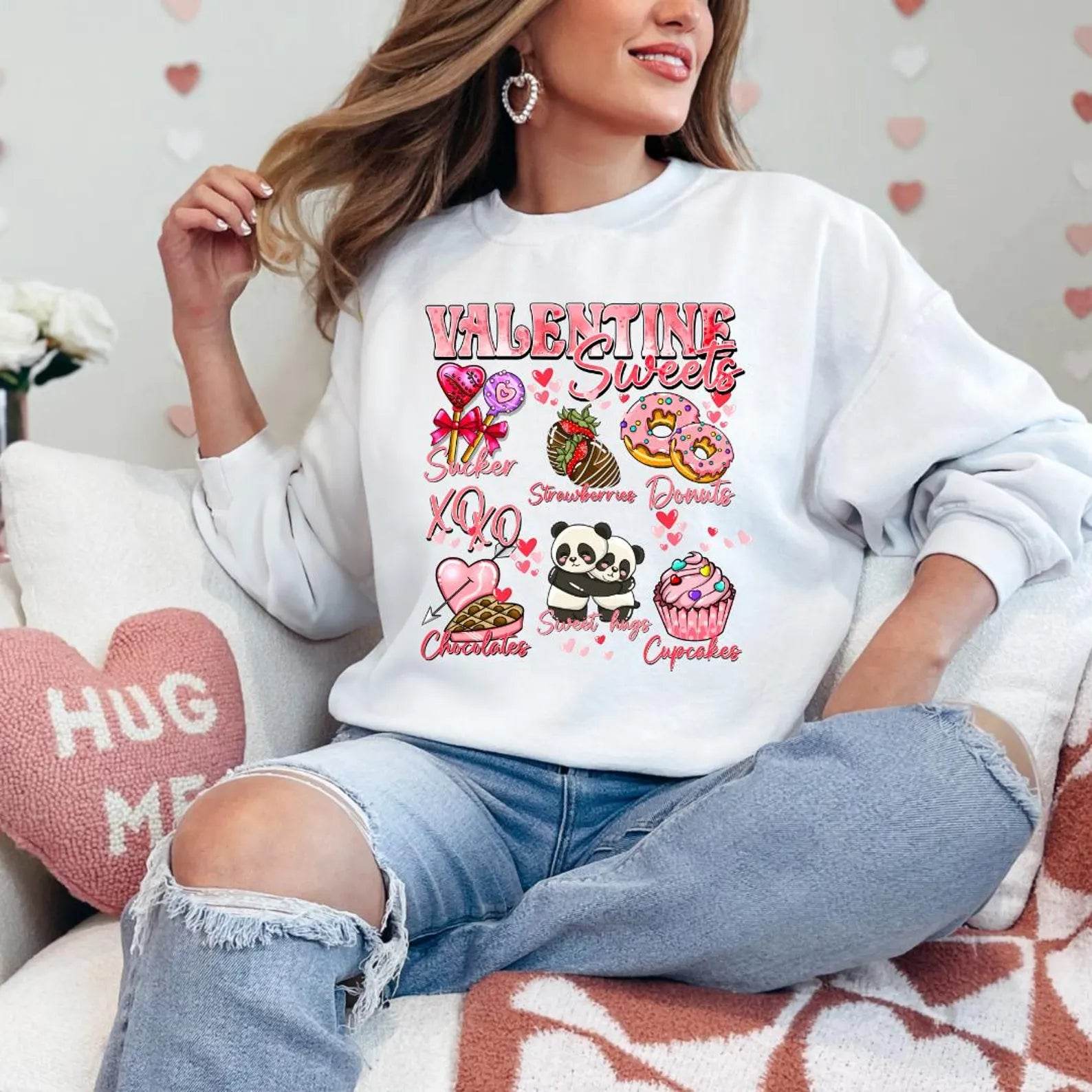 A woman sitting and smiling, wearing a white sweatshirt with a Valentine's Day-themed graphic, surrounded by red heart-shaped balloons.valentines-sweatshirt-for-women