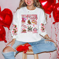 A woman sitting and smiling, wearing a black sweatshirt with a Valentine's Day-themed graphic, surrounded by red heart-shaped balloons.valentines-sweatshirt-for-women