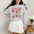 A woman sitting and smiling, wearing a sweatshirt with a Valentine's Day-themed graphic, surrounded by red heart-shaped balloons.valentines-sweatshirt-for-women