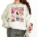 A woman sitting and smiling, wearing a sweatshirt with a Valentine's Day-themed graphic, surrounded by red heart-shaped balloons.valentines-sweatshirt-for-women