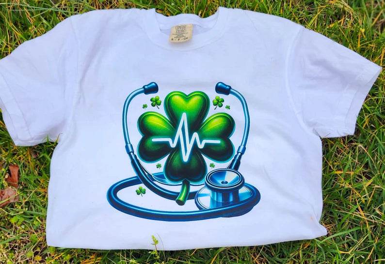 White  Heartbeat Stethoscope T-Shirt, lying on a grassy surface.