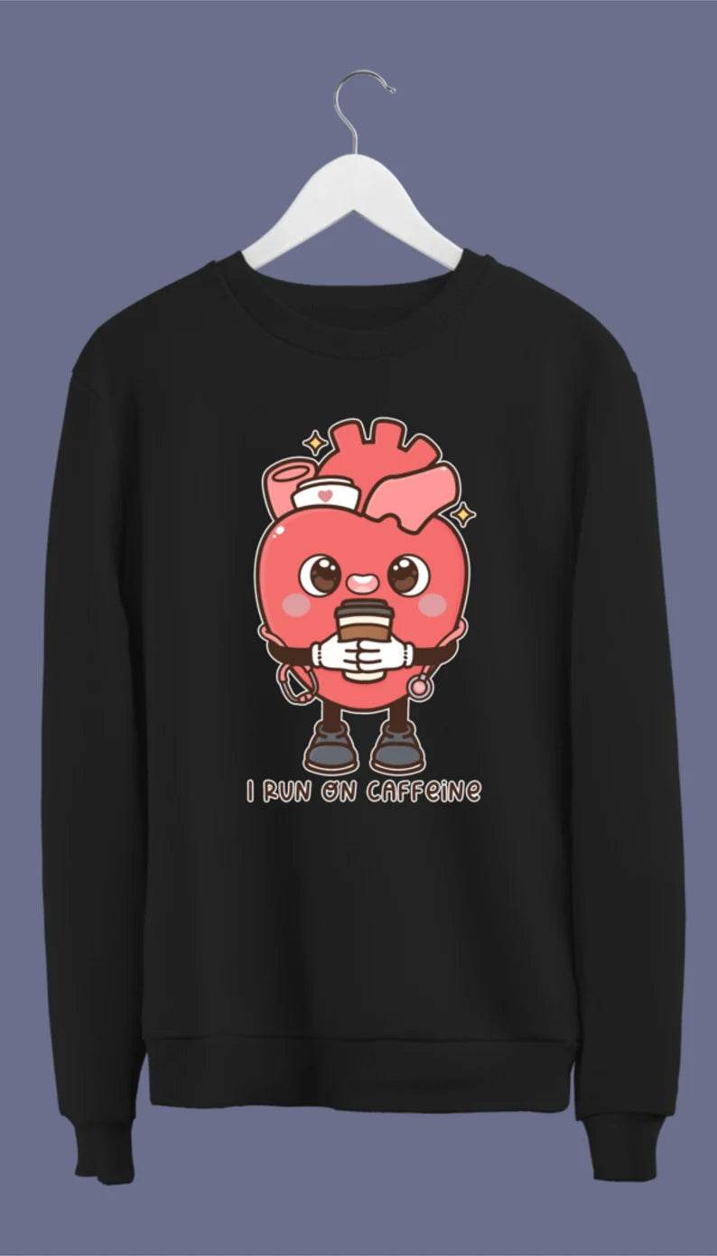 A black crewneck sweatshirt with a graphic of an anatomical heart holding a coffee cup and the phrase 'I live on caffeine.'.