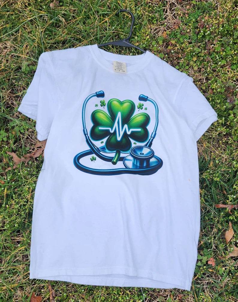 White  Heartbeat Stethoscope T-Shirt, lying on a grassy surface.