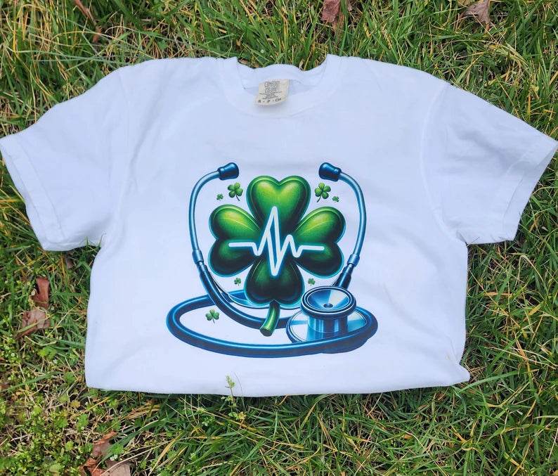White  Heartbeat Stethoscope T-Shirt, lying on a grassy surface.