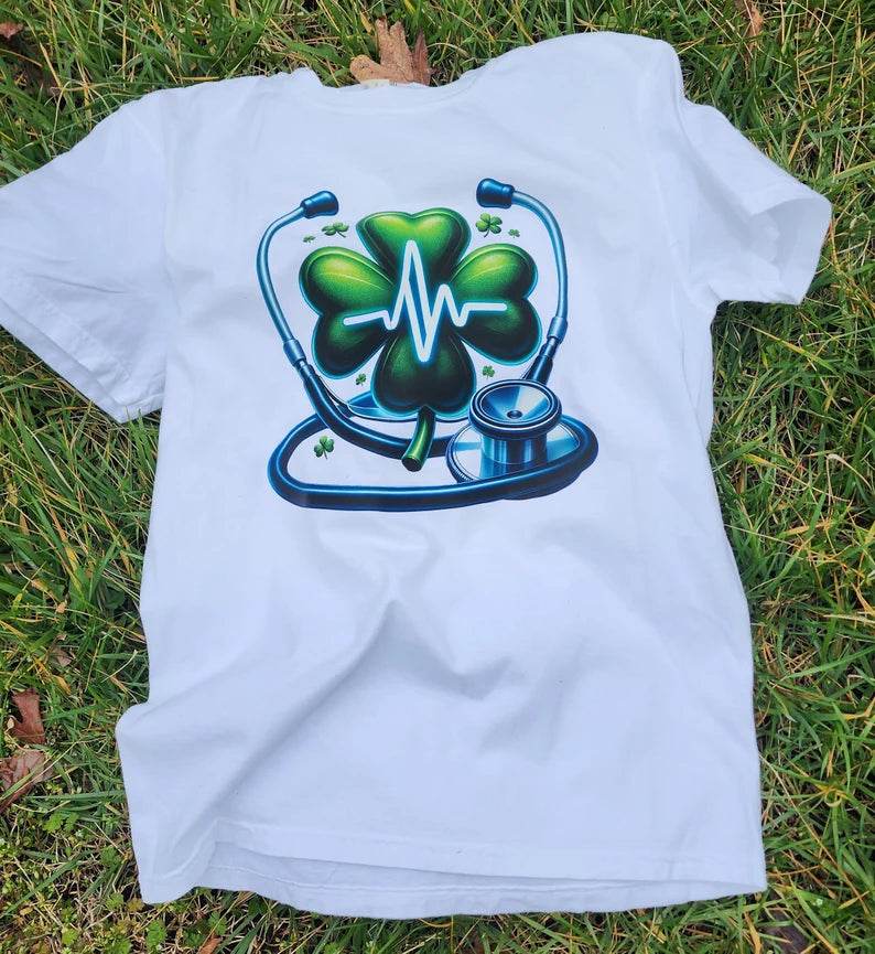 White  Heartbeat Stethoscope T-Shirt, lying on a grassy surface.