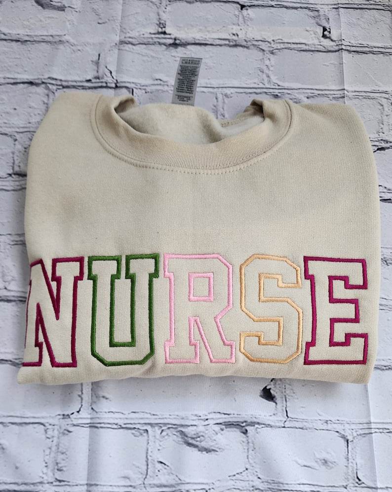 A collection of embroidered crewneck sweatshirts with the word 'NURSE' and 'registered NURSE' embroidered 