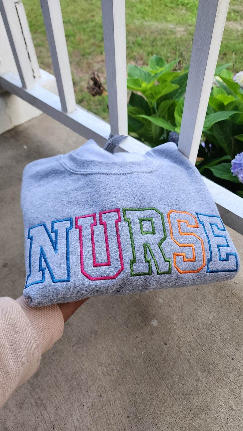 A collection of embroidered crewneck sweatshirts with the word 'NURSE' and 'registered NURSE' embroidered 