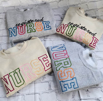 A collection of embroidered crewneck sweatshirts with the word 'NURSE' and 'registered NURSE' embroidered in various colors.